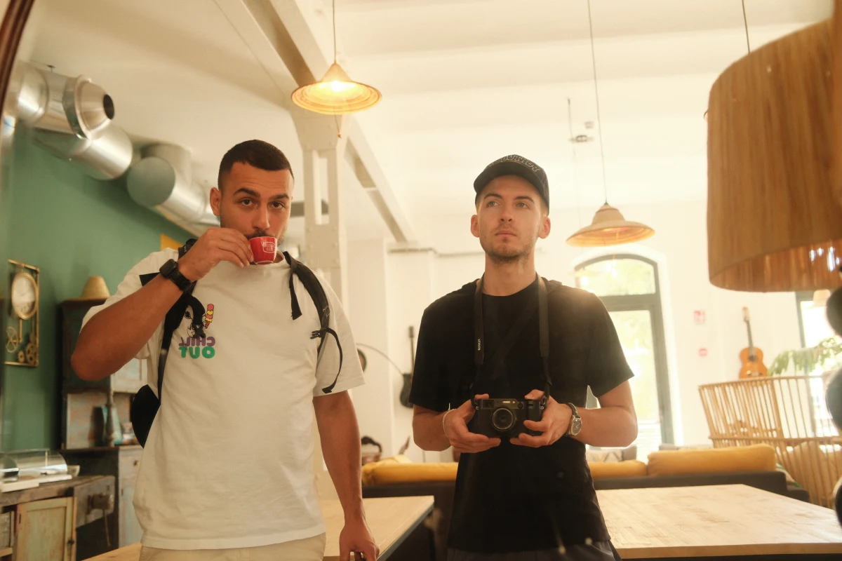 Dylan holding a camera in a cafe with a friend