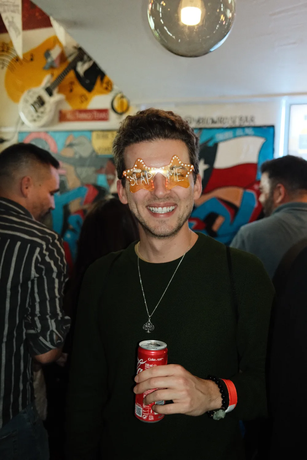 Dylan wearing novelty star sunglasses at a bar, holding a Coke